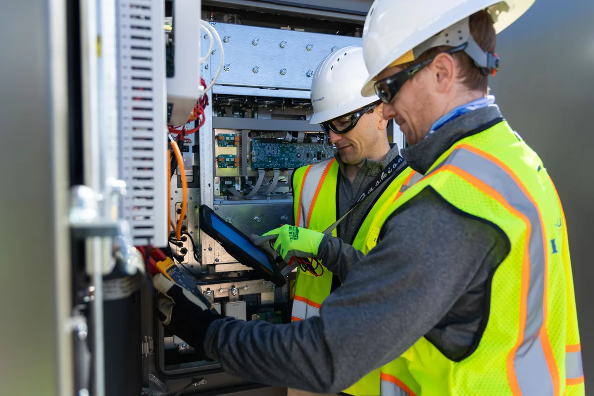 Engineers commissioning a containerized ESS with a tablet
