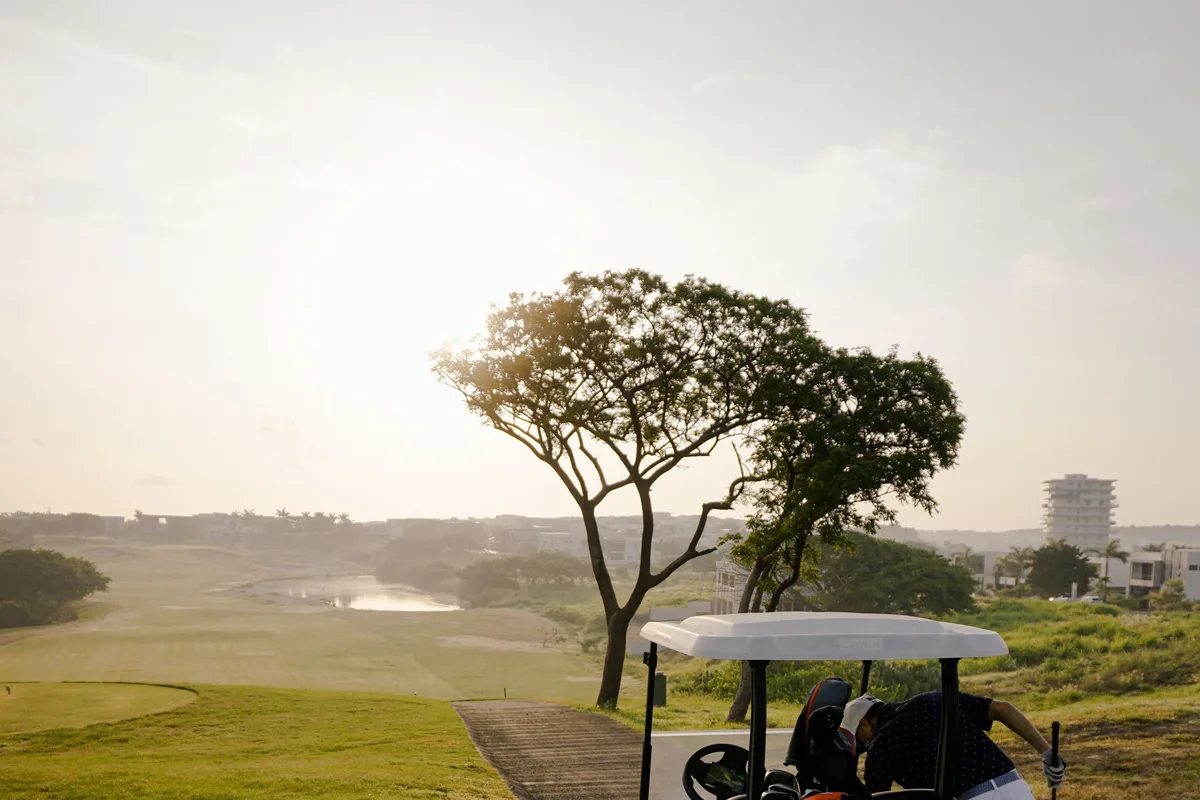 Golf cart driving along a course path at sunset, representing a standardised multi-site fleet