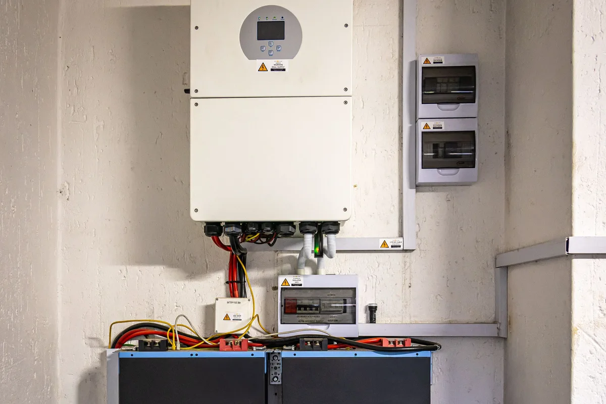 Four rack-mounted batteries wired in parallel beneath a wall inverter for capacity expansion