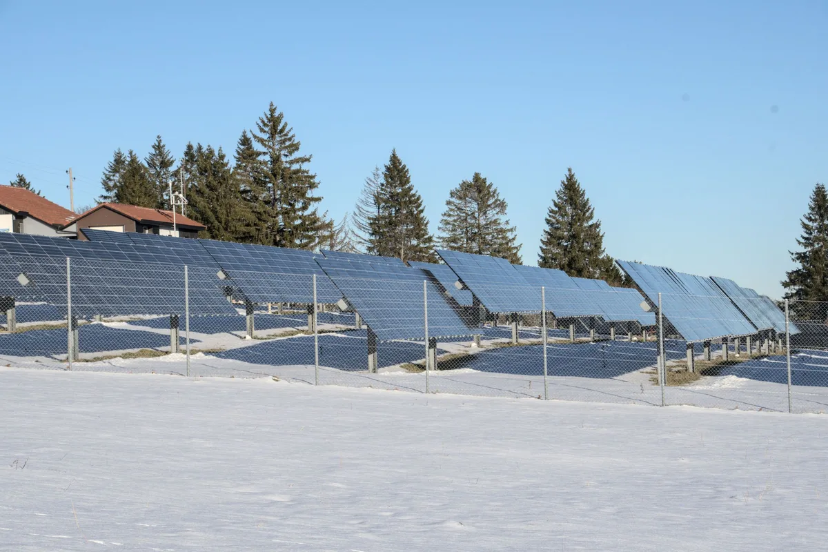 Ground-mounted solar array in a snowy field, illustrating cold-weather charging