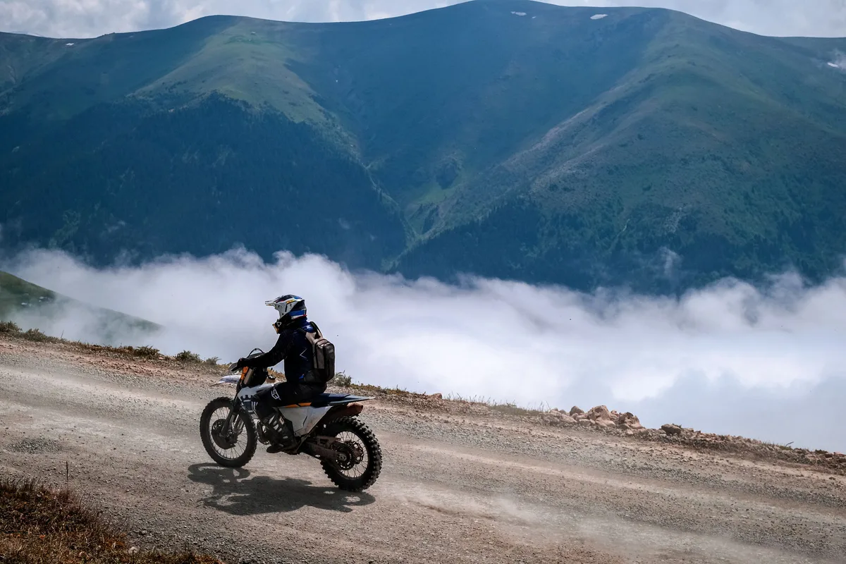 Electric two-wheeler rider climbing a misty mountain road, illustrating hill-terrain duty